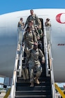 A photo of Airmen walking down stairs from an aircraft.