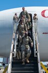 A photo of Airmen walking down stairs from an aircraft.