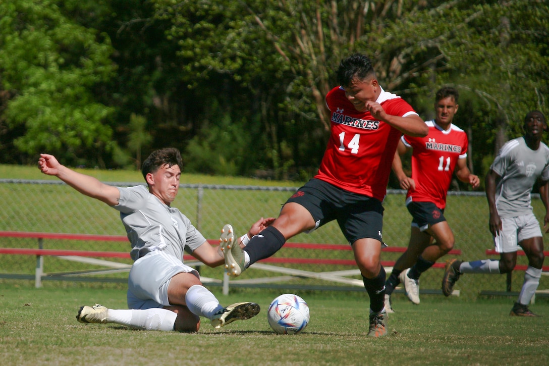 Air Force 1st Lt. Michael Neacsu of Hanscom AFB, Mass. hits the slide tackle from Marine Cpl. Omar Esquivel of MCB Camp Lejeune, N.C. during the first match of the 2024 Armed Forces Men's Soccer Championship hosted by Marine Corps Logistics Base Albany, Georgia at Albany State University from April 2-10.  The Armed Forces Championship features teams from the Army, Marine Corps, Navy (with Coast Guard players), and Air Force (with Space Force players).  Department of Defense Photo by Mr. Steven Dinote - Released.