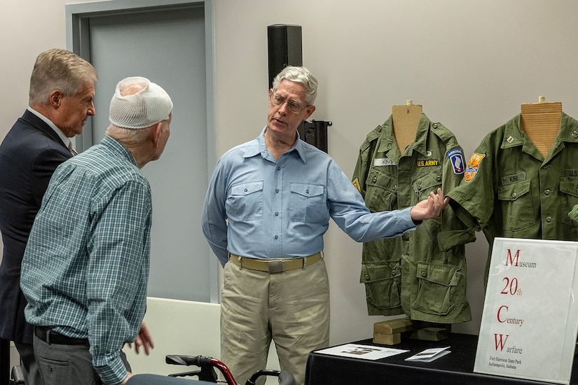 Chris Schneider, Museum of 20th Century Warfare president, describes a U.S. Army Vietnam War-era uniform to Stan Soderstrom, the civilian aide to the Secretary of the Army for Indiana, left, and retired U.S. Army Mater Sgt. Robert Cansler after the U.S. Army Financial Management Command’s Vietnam War commemoration at the Maj. Gen. Emmett J. Bean Federal Center in Indianapolis March 25, 2024. Cansler enlisted in the U.S. Army in 1961, served as a flight engineer on the Army’s newly minted AC-1 and CV-2 Caribou aircraft, served two tours in Vietnam, and eventually transferred to the Army’s Finance Corps as an accountant. (U.S. Army photo by Mark R. W. Orders-Woempner)