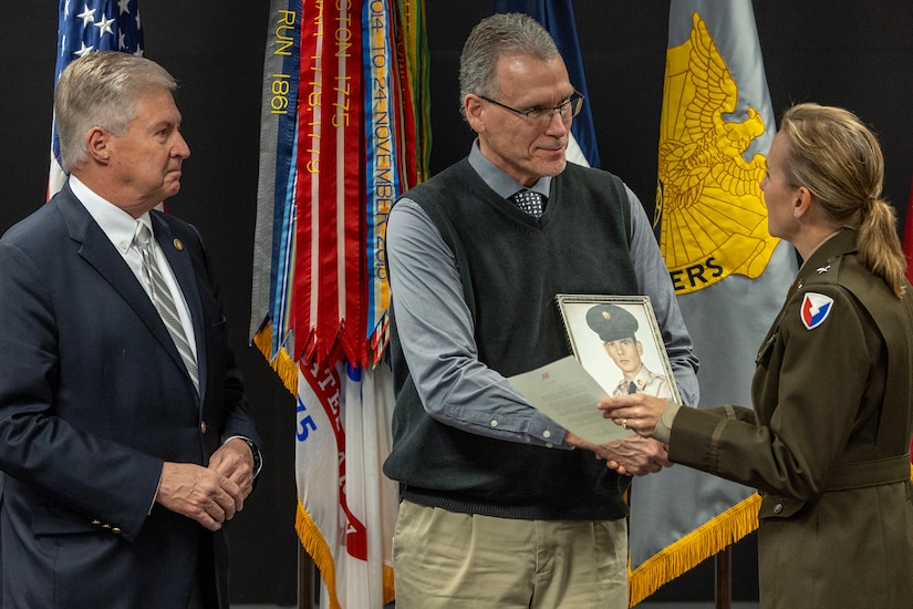 Brig. Gen. Paige M. Jennings, U.S. Army Financial Management Command commanding general, presents a one-star note to Ralph Carie, the son-in-law of former U.S. Army Spc. 4 Lyle Kenneth Stoddard, as Stan Soderstrom, the civilian aide to the Secretary of the Army for Indiana, prepares to give him a Vietnam War lapel pin during USAFMCOM’s Vietnam War commemoration at the Maj. Gen. Emmett J. Bean Federal Center in Indianapolis March 25, 2024. Stoddard, who passed away last year, served one tour in Vietnam as a transportation specialist with Company B, 170th Transportation Battalion, 11th Air Assault Division. (U.S. Army photo by Mark R. W. Orders-Woempner)