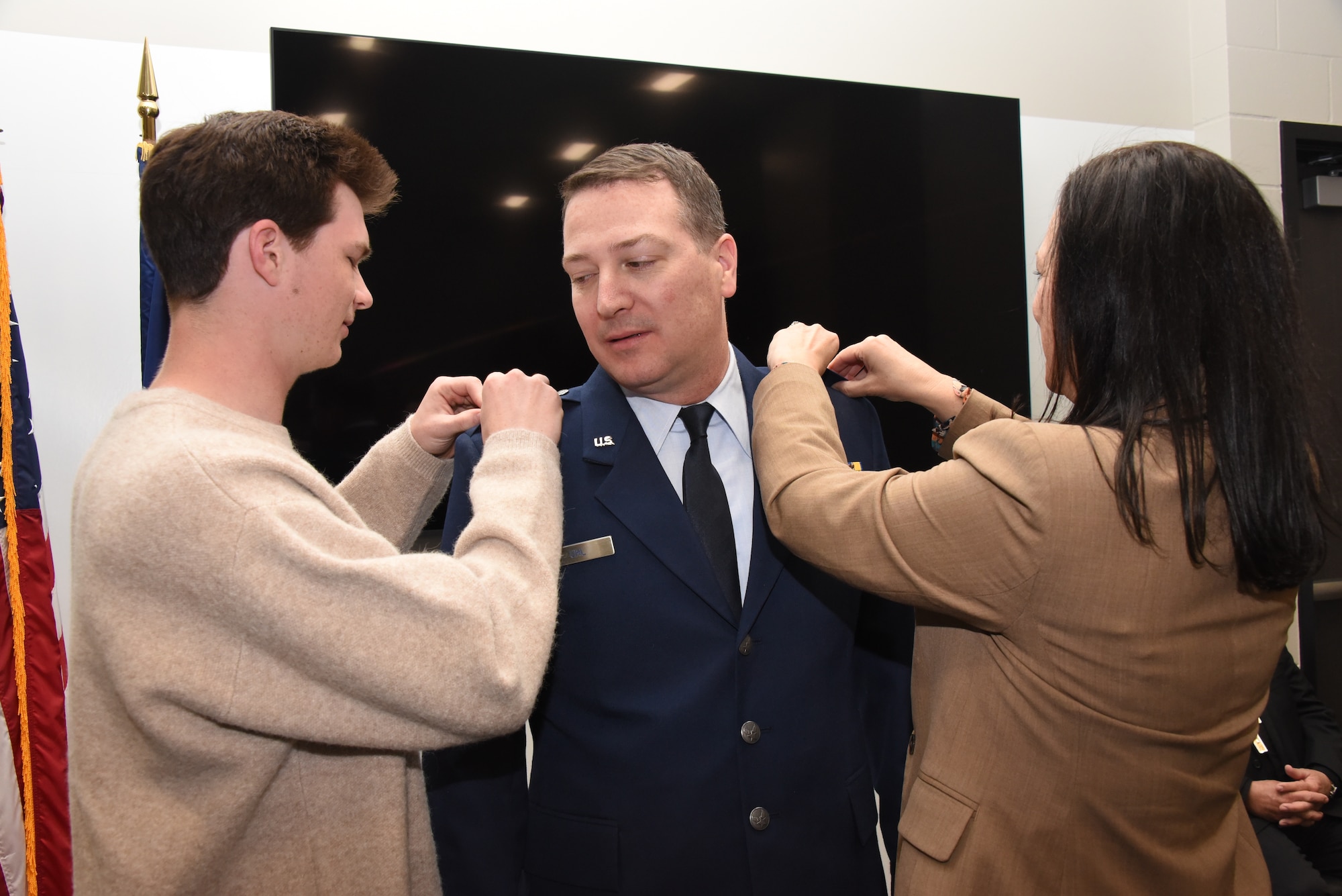 U.S. Air National Guard Col. Benjamin Uhl, the Director of Operations for Iowa Air National Guard, center, has his colonel ranks pinned on by his wife and son
