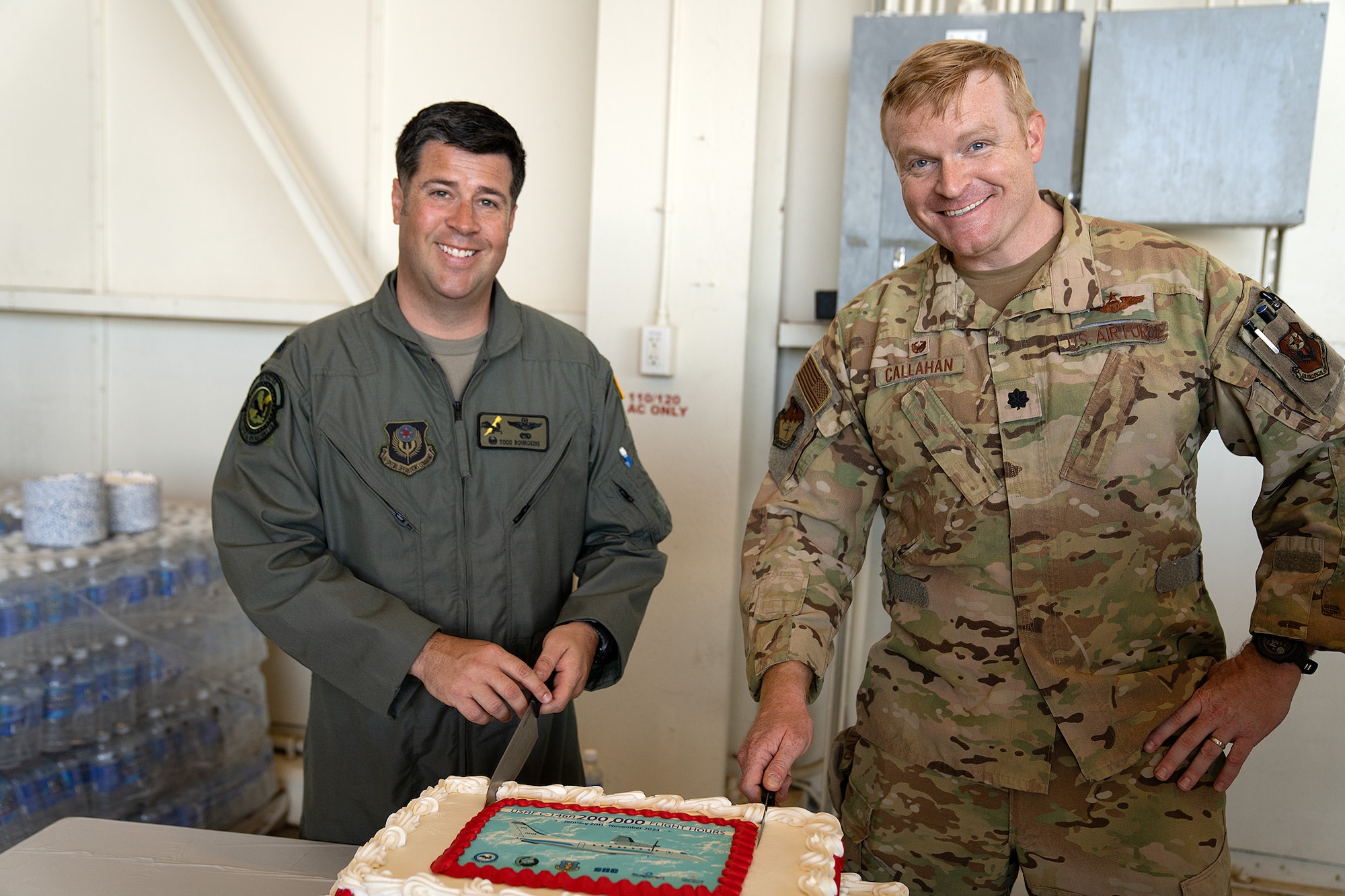 Two men in military uniform slice a decorated cake
