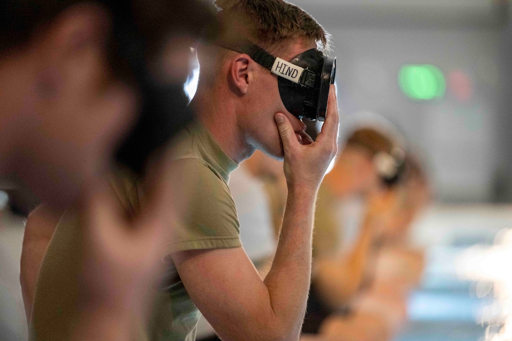 Special Warfare Training Wing trainees with goggles on prepare to enter the pool for an underwater demonstration.