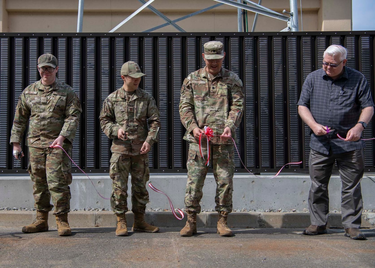 Three military members and a civilian cut a ribbon.
