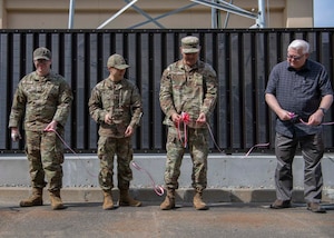 Three military members and a civilian cut a ribbon.