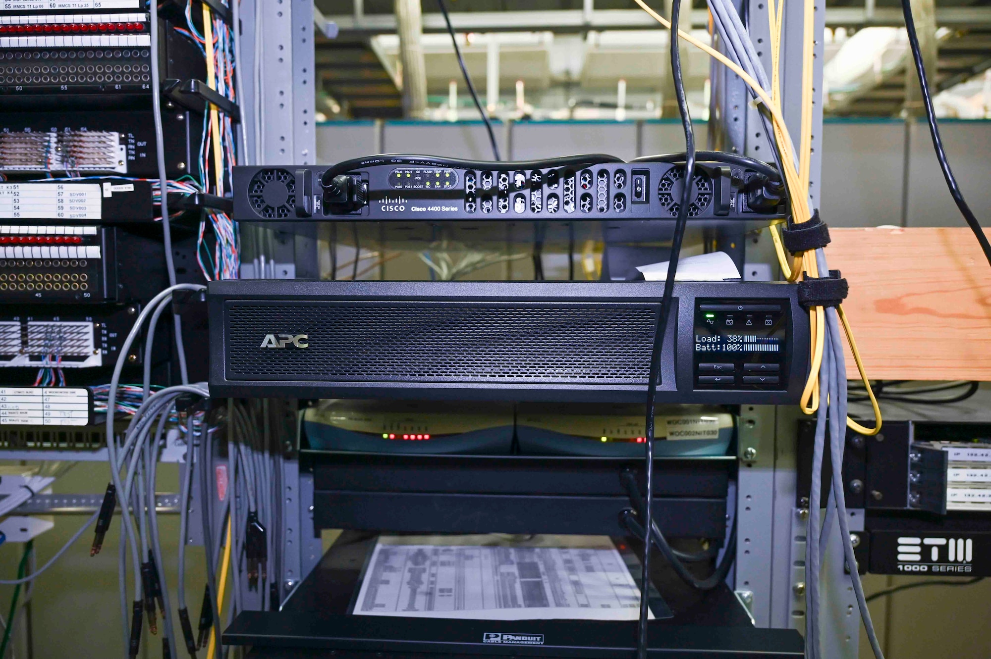 A phone system box with wires sits on a shelf