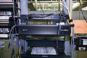 A phone system box with wires sits on a shelf