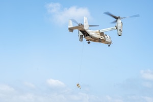 An Airman is suspended from an MV-22 Osprey tiltrotor aircraft.