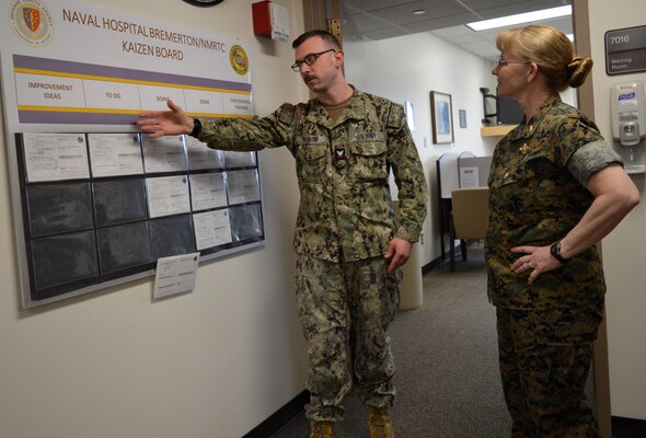 Initiative described...Hospital Corpsman 2nd Class Matthew North, NHB/NMRTC Bremerton Mental Health department leading petty officer, describes several of his department’s continuous process improvement initiatives to U.S. Navy Rear Adm. Pamela Miller, medical officer of the Marine Corps during her visit, April 4, 2024. The Kaizen Board concept is utilized throughout the command to visually assist clinical and departmental staff to openly engage in taking part in  coordinating creative thinking through a developmental process into actual procedures in place (Official Navy photo by Douglas H Stutz, NHB/NMRTC Bremerton, public affairs officer).