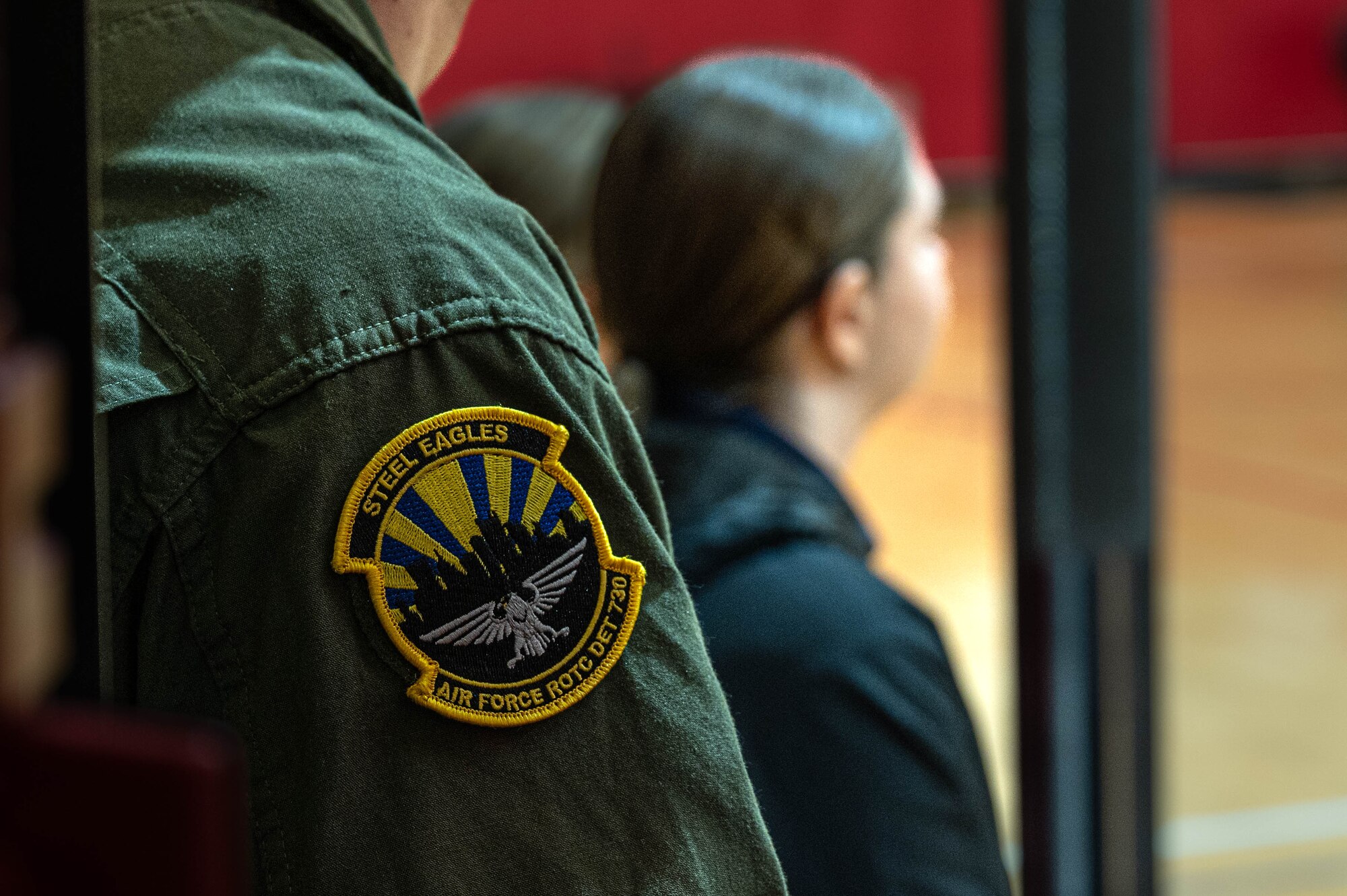 A blue, black, and gold patch is displayed on a green uniform