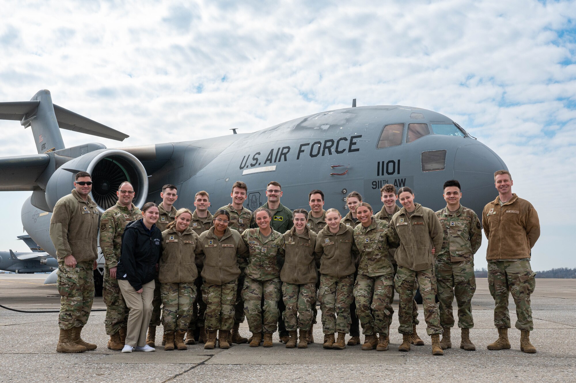 A group of people in uniform poses for a photo in front of a military aircraft