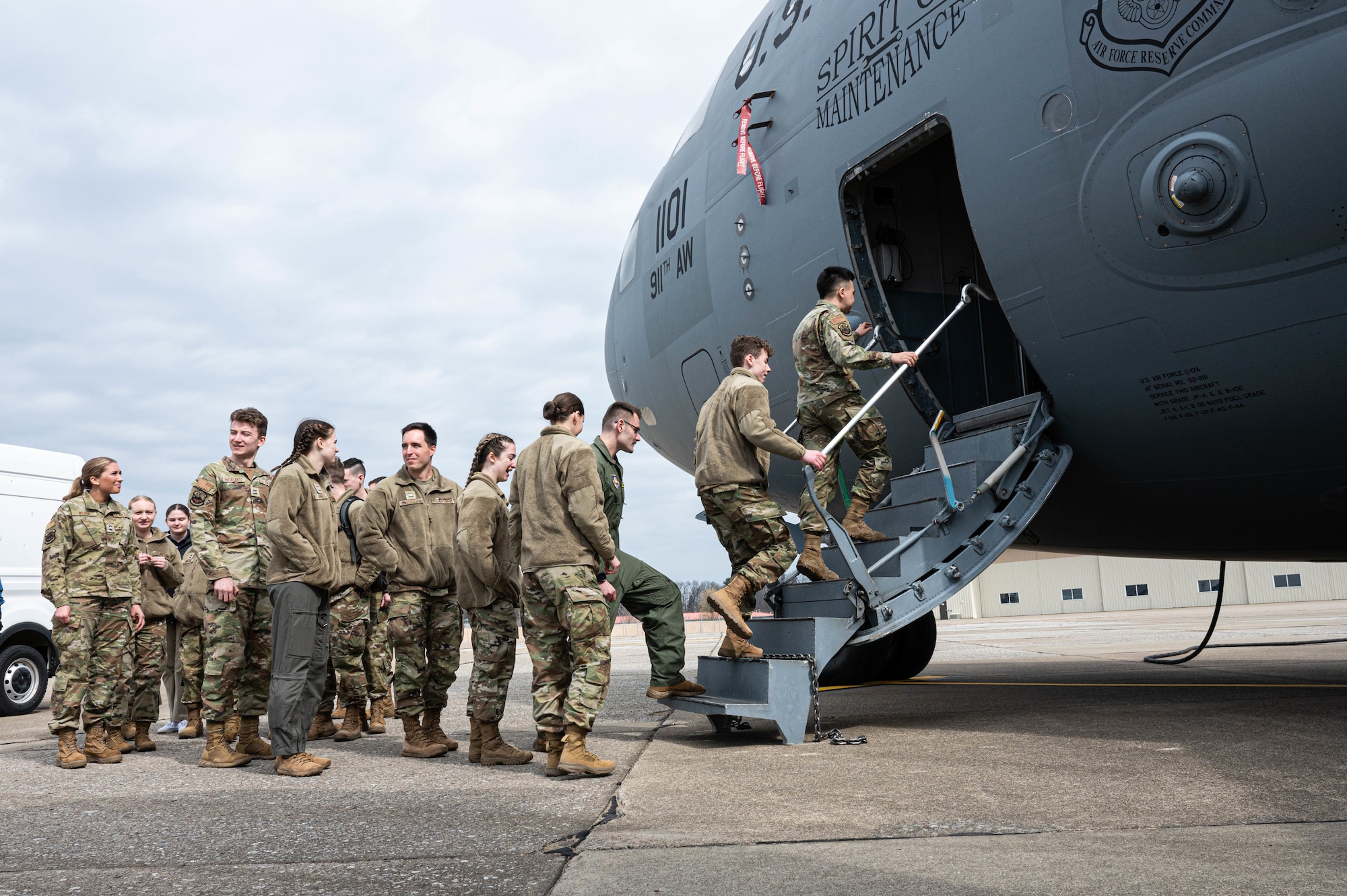 A group of people in uniform lines up to board a military aircraft