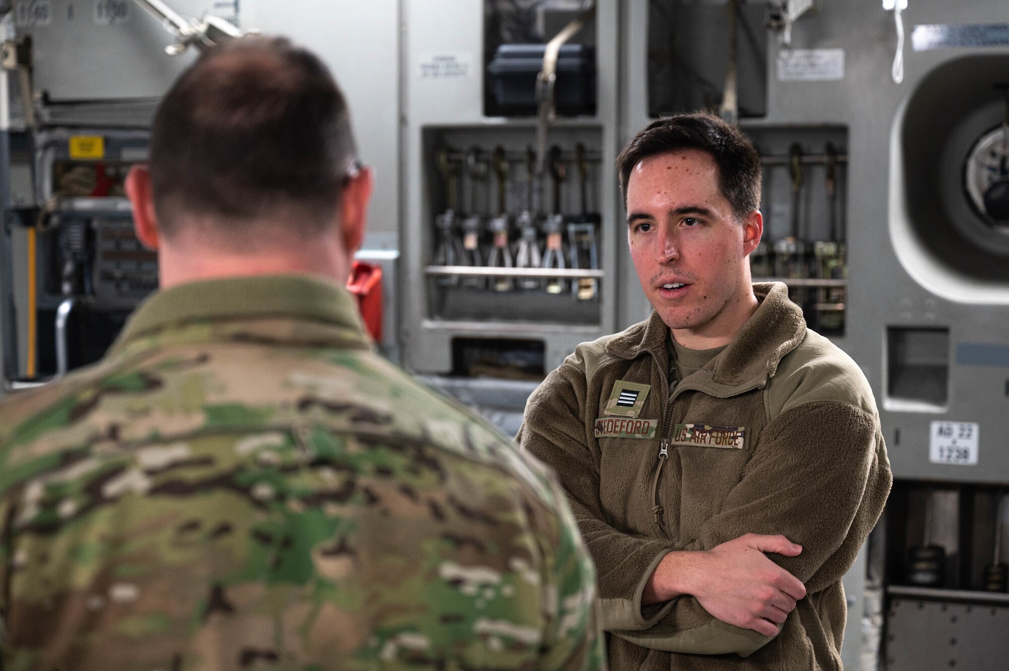 A man in uniform speaks to another military member