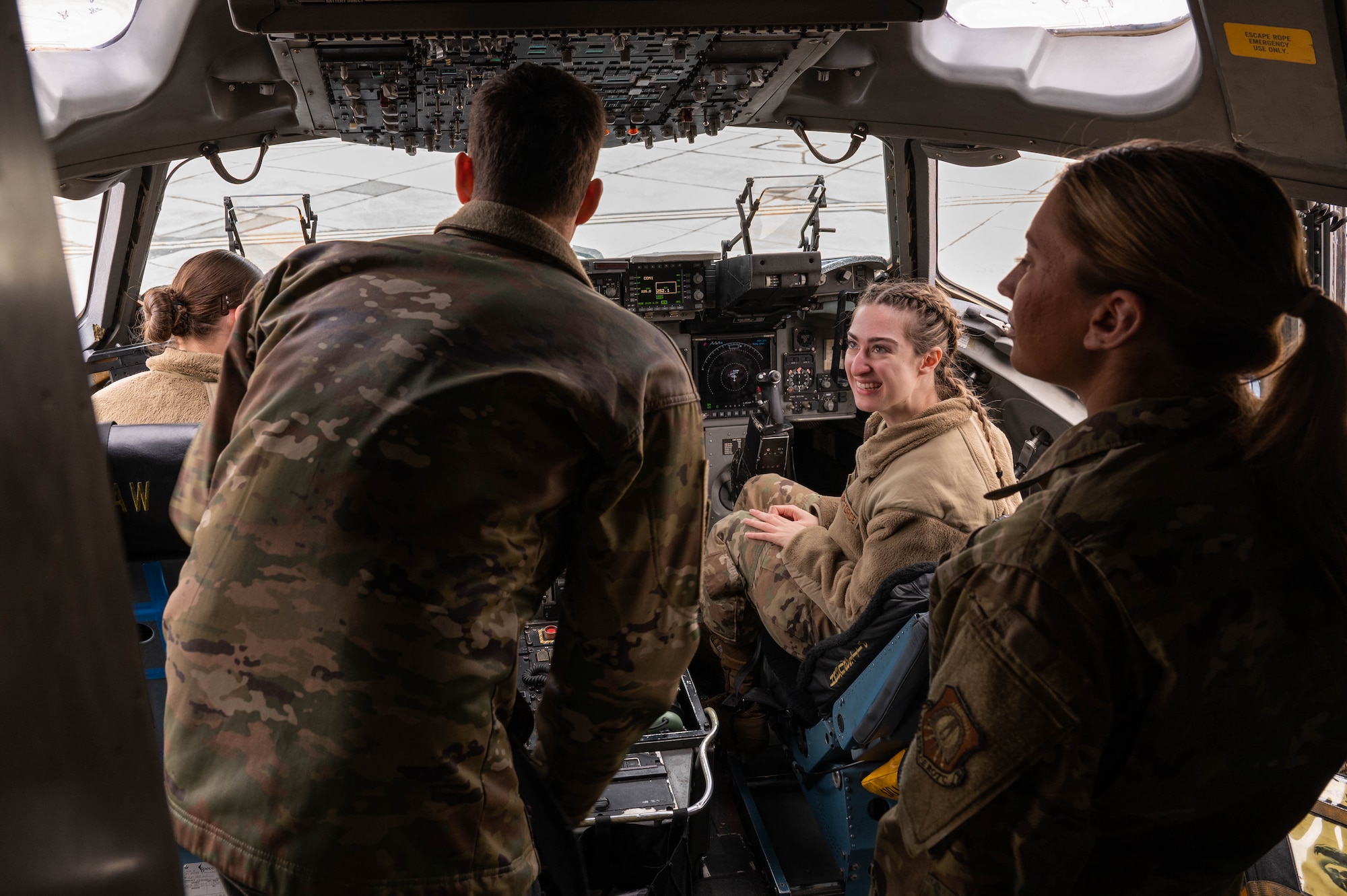 A group of people in uniform sit in a C-17 Globemaster III cockpit