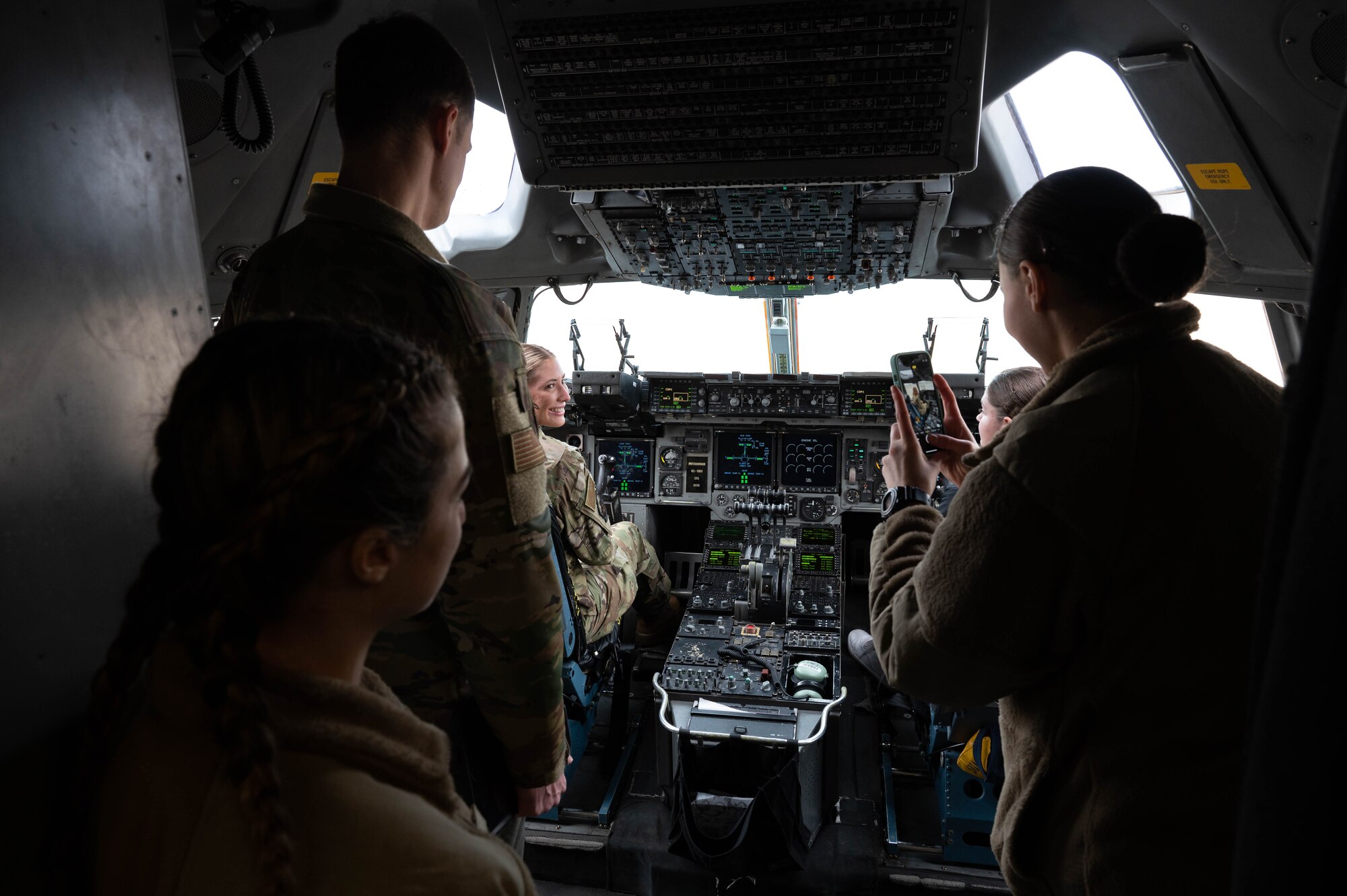 A group of people in uniform sit in a C-17 Globemaster III cockpit