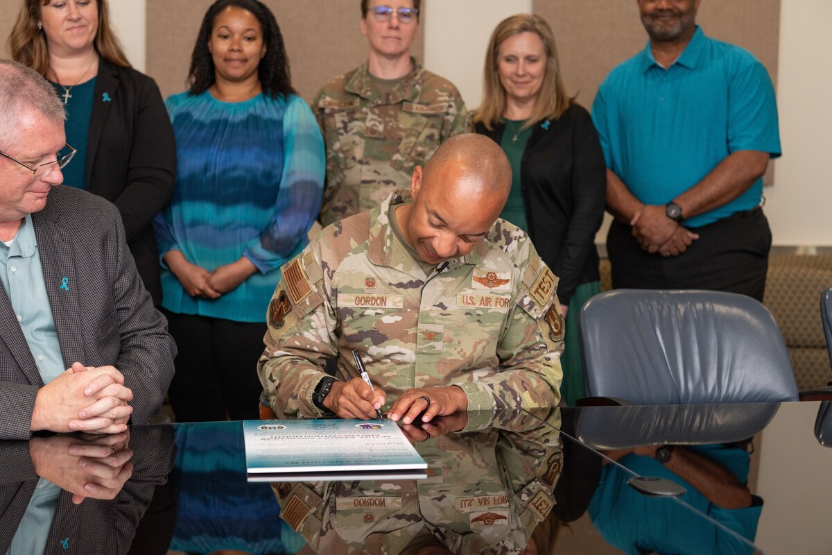 Arnold Engineering Development Complex Commander Col. Randel Gordon signs a proclamation April 1, 2024, at Arnold Air Force Base, Tenn., declaring April as Sexual Assault Awareness and Prevention Month at Arnold.  Pictured to Gordon’s right is Gary Johnson, Sexual Assault Response Coordinator at Arnold AFB. Pictured standing from left are Sexual Assault Victim Advocates Nicole Berger and Kayla Vance, AEDC Senior Enlisted Leader Chief Master Sgt. Jennifer Cirricione, Prevention Specialist Joey Vap, and Integrated Prevention and Response Director Lee Smith. (U.S. Air Force photo by Keith Thornburgh)