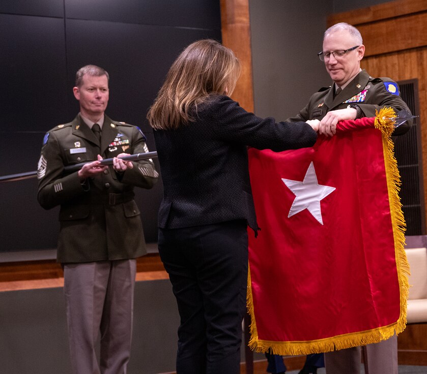 Newly promoted U.S. Army Brig. Gen. Michael Eastridge, of Plymouth, Michigan, Deputy Assistant Adjutant General, Illinois Army National Guard, and his partner, Mary Gollan, unfurl Eastridge’s general officer flag during a promotion ceremony April 6 at the Illinois Military Academy, Camp Lincoln, Springfield, Illinois.