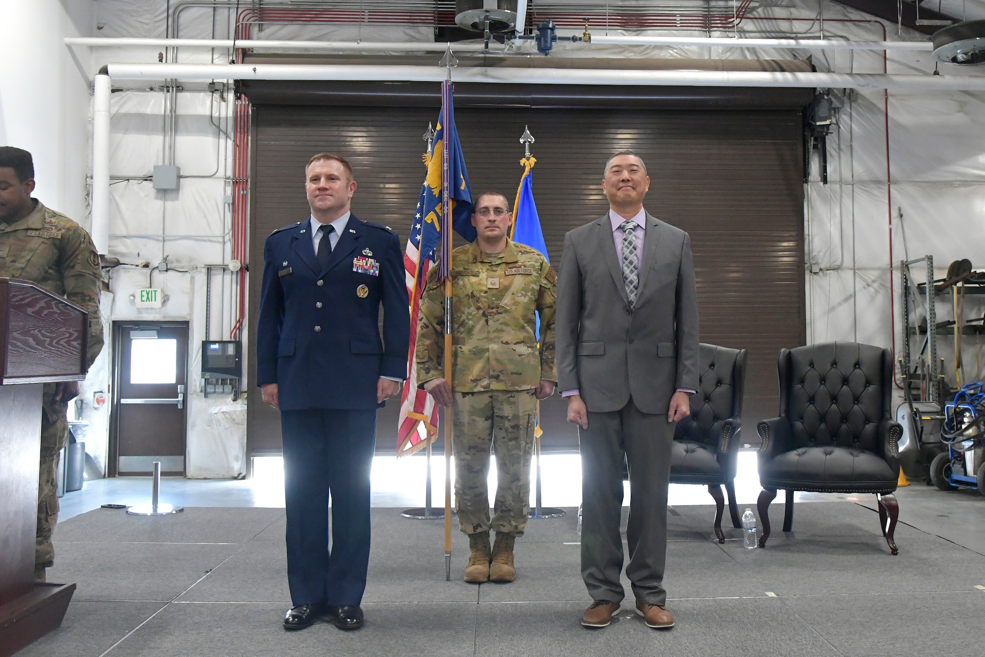 Peter Feng, Col Holland, and Master Sgt. Strauss stand at attention during the ceremony.