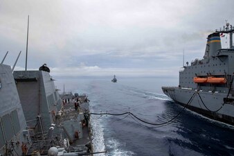 USS Ralph Johnson (DDG 114) replenishes from the fleet replenishment oiler USNS Yukon (T-AO 202) as USS Howard (DDG 83) approaches in the Philippine Sea.