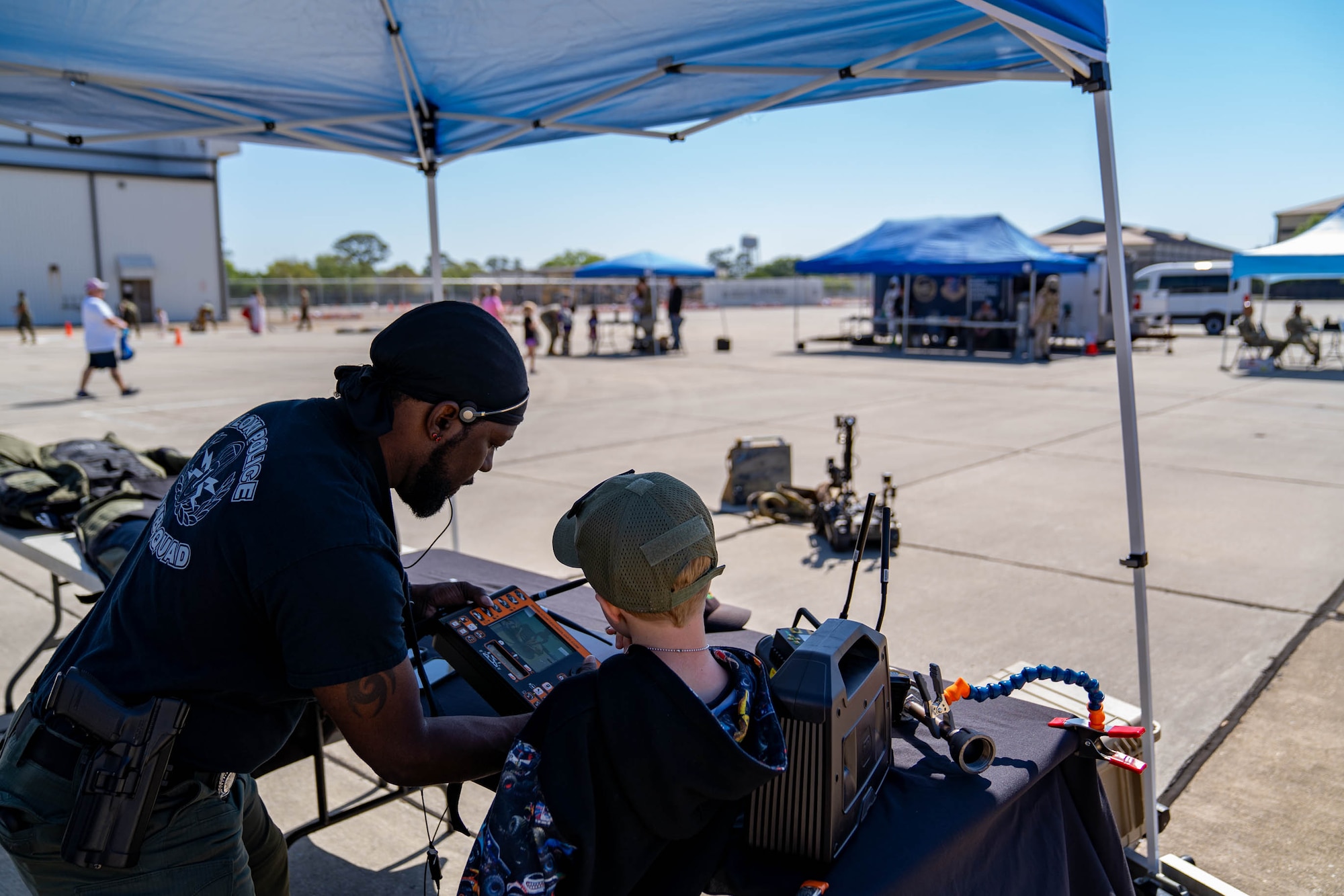 Sgt. Rodgerick Wiggins, Biloxi Bomb Squad public safety bomb technician, helps a military child direct a robot to inspect a suspicious package at Operation HERO at Keesler Air Force Base, Mississippi, April 6, 2024.