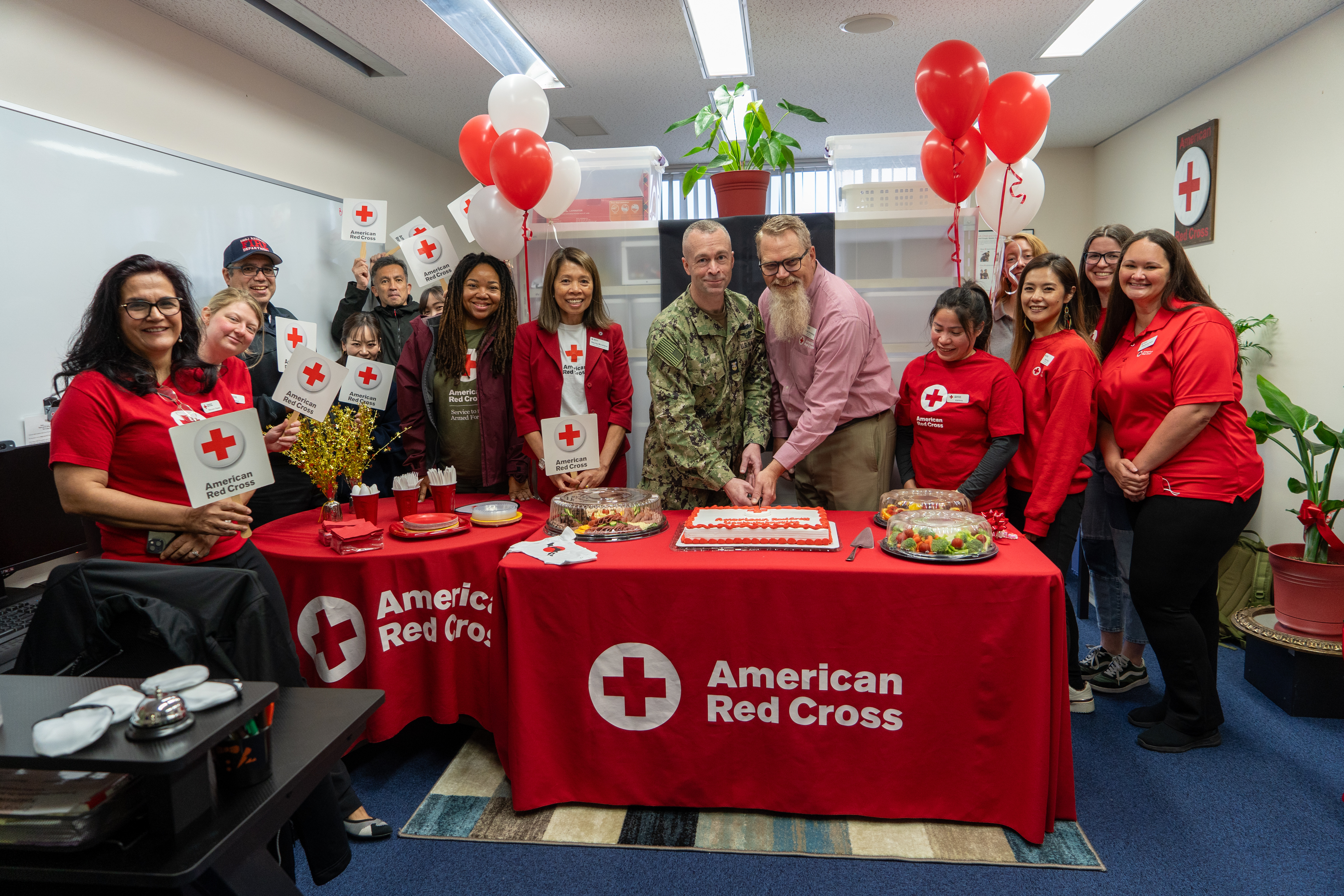 Scott Armstrong, Division Director of the Asia Pacific Division for the American Red Cross and Command Master Chief Dennis Hunt, Commander, Fleet Activities Yokosuka (CFAY) command master chief cut a ceremonial cake during the grand re-opening celebration for the American Red Cross Yokosuka office.
