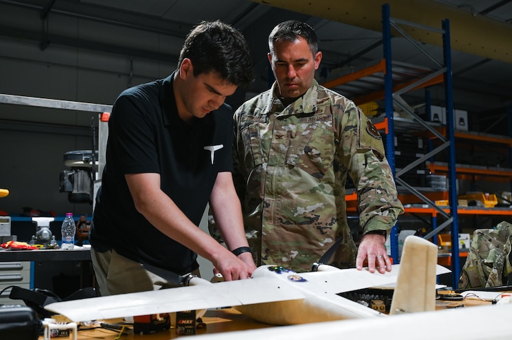 Two people work on a model aircraft in a workshop