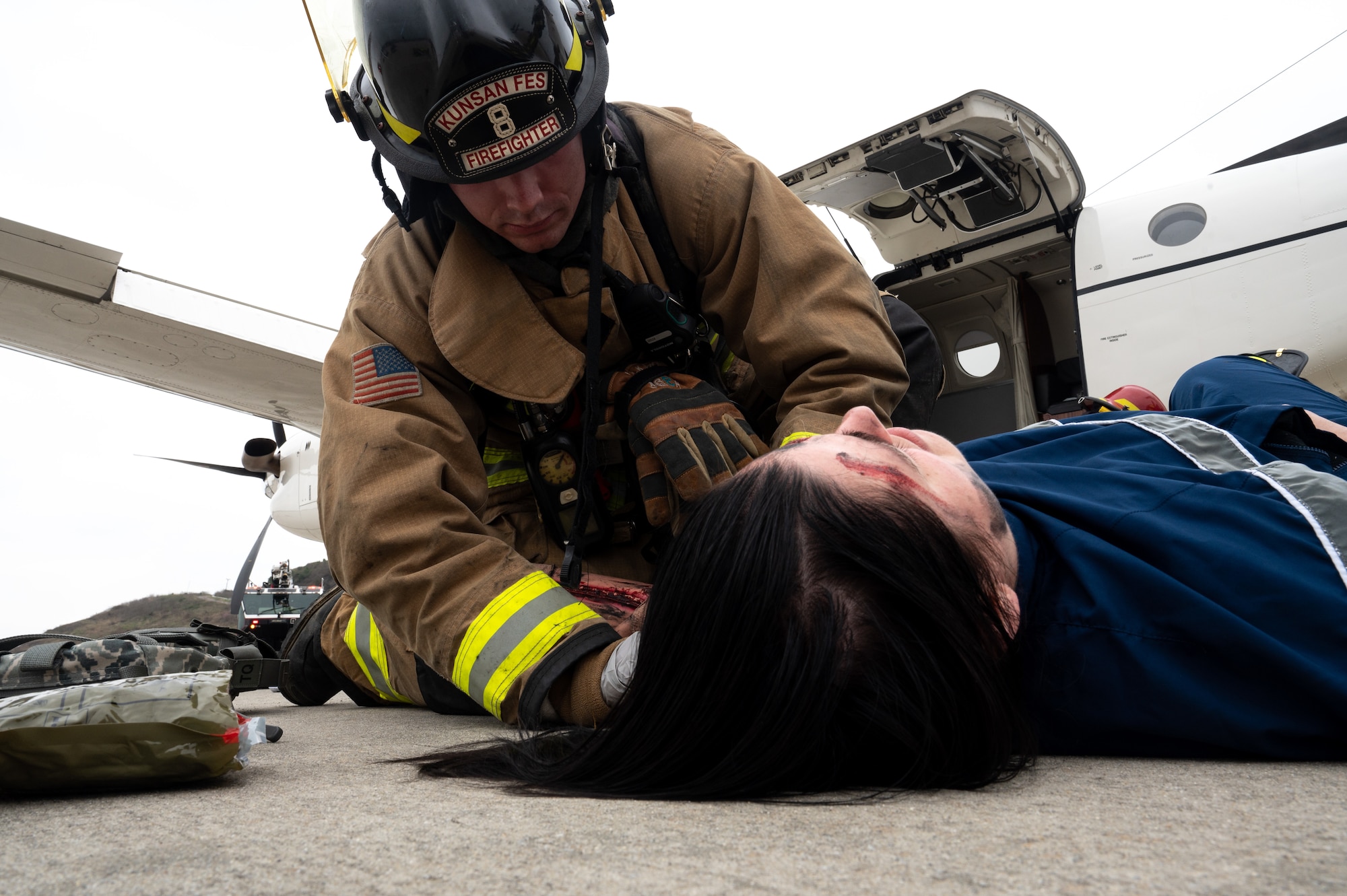 Simulated victim laying on the ground while a firefighter attends to them during an exercise.