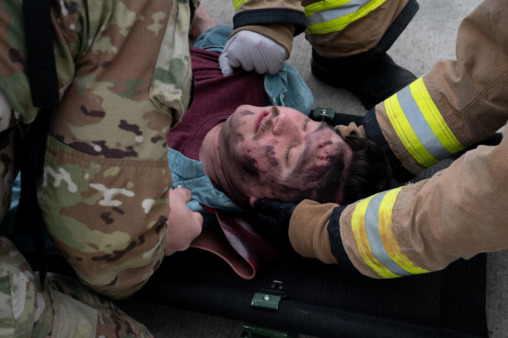 Medical personnel and firefighters attend to a person laying on the ground during an exercise.