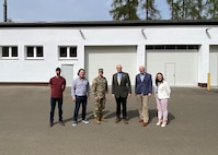 Joseph Scheff, the deputy to the commander at 405th Army Field Support Brigade, and Command Sgt. Maj. Terrell Brisentine, the 405th AFSB command sergeant major, pose for a photo with the depot forward repair area team in front of the newly renovated and modernized Tobyhanna Army Depot Forward Repair Area-Europe maintenance facility on Panzer Kaserne in Kaiserslautern.