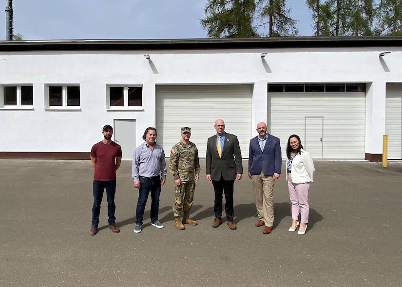 Joseph Scheff, the deputy to the commander at 405th Army Field Support Brigade, and Command Sgt. Maj. Terrell Brisentine, the 405th AFSB command sergeant major, pose for a photo with the depot forward repair area team in front of the newly renovated and modernized Tobyhanna Army Depot Forward Repair Area-Europe maintenance facility on Panzer Kaserne in Kaiserslautern.