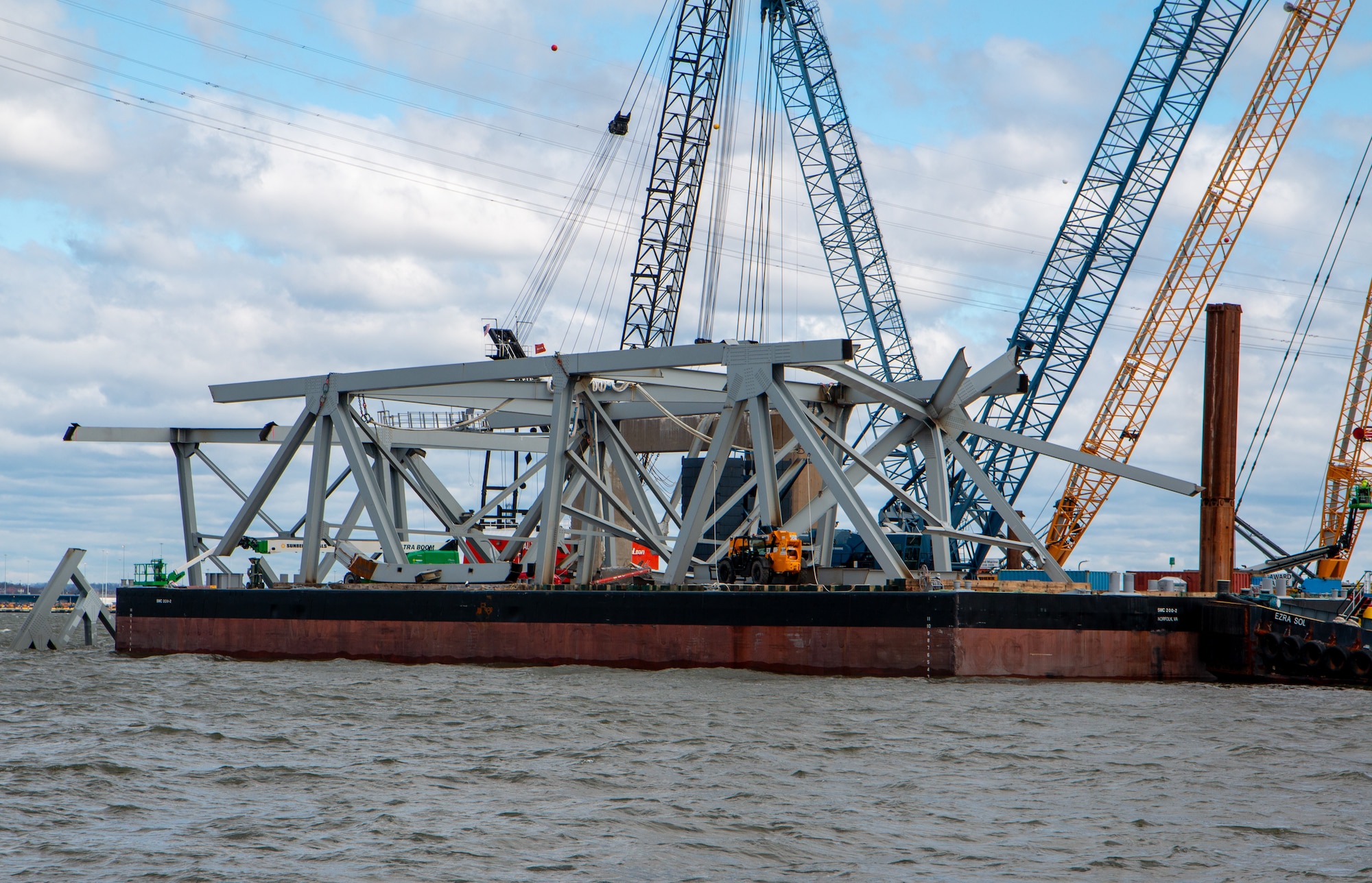 A portion of the Francis Scott Key Bridge is transported by barge.