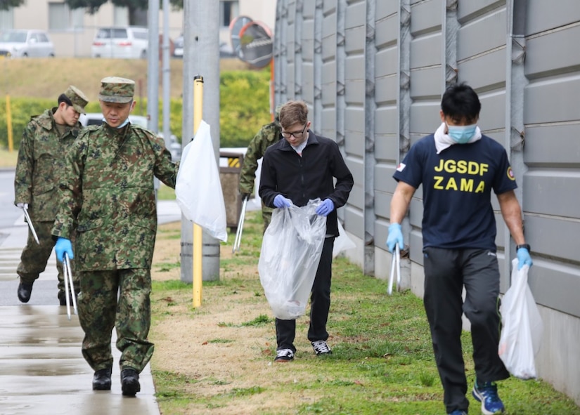 U.S. and Japanese soldiers pick up trash.