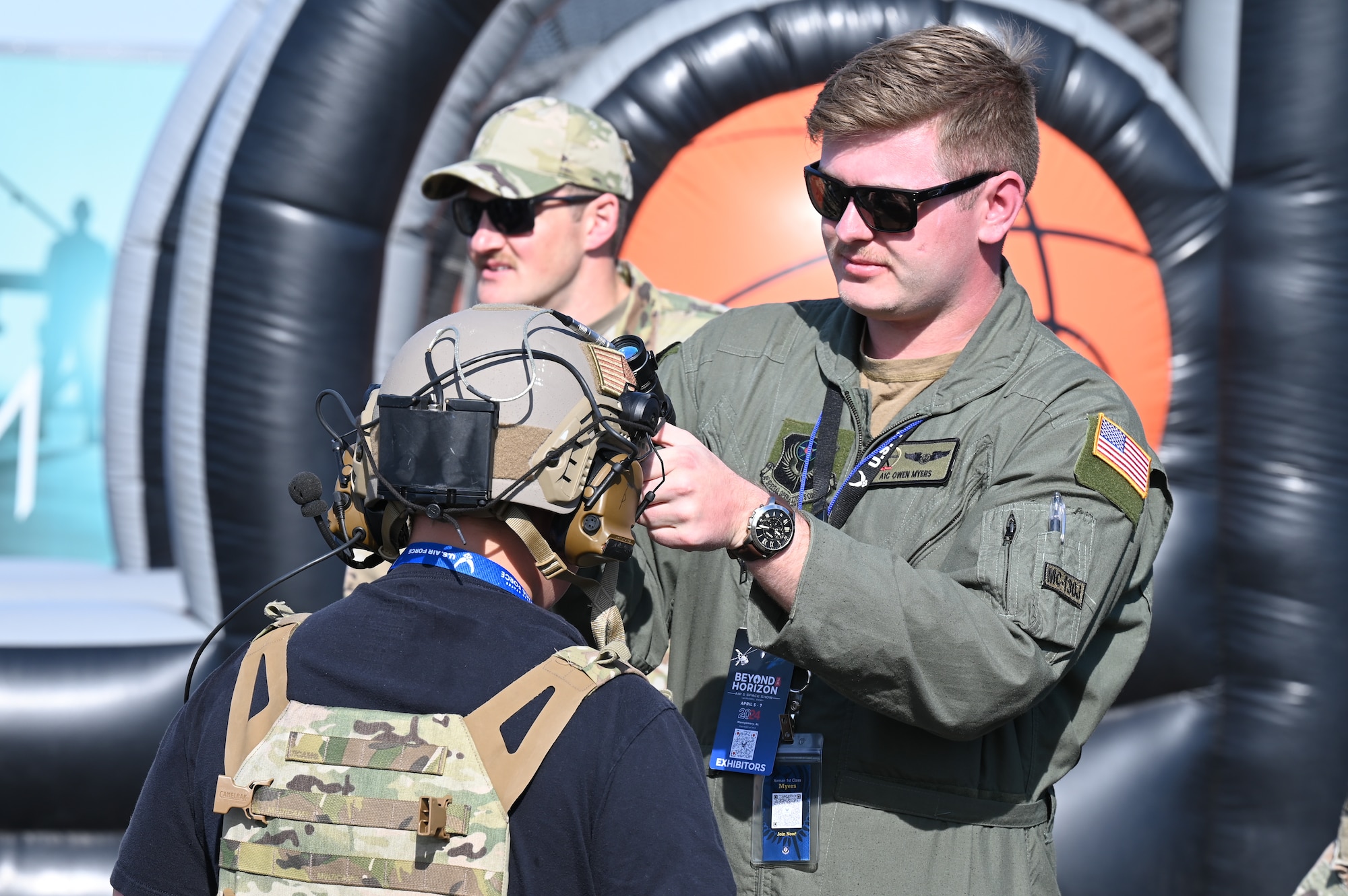 Air force personnel demonstrates the use of a helmet to a spectator during the Beyond the Horizon Air and Space Show at Maxwell Air Force Base, Ala. April 7, 2024. The air and space show boasted a variety of activities, including military and civilian aerial demonstrations, static display aircraft, and a STEM expo.  (U.S. Air Force photo by Senior Airman Evan Porter)