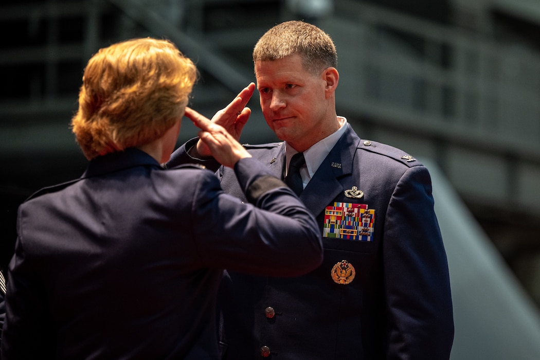 A man faces a woman as they salute each other.