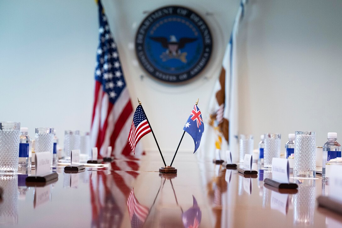Small U.S. and Australian flags sit at a long table.