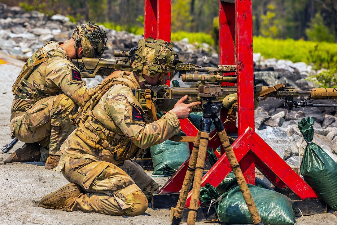 Two soldiers kneel while looking through the scopes of their weapons during a competition.
