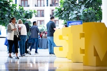 Attendees enter the main exhibit area for the Sea-Air-Space Science, Technology, Engineering, and Math (STEM) expo at the Gaylord National Hotel and Conference Center, Sunday. The entrance to the exhibits was lined with large-sized yellow letters S T E and M as a welcome to the expo. Conference goers had the opportunity to participate in hands-on science activities and experience interactive exhibits based on STEM concepts with more than 20 exhibitors from various Department of Defense service branches.