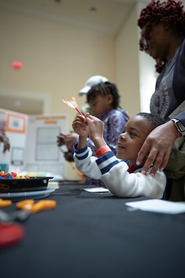 An elementary-aged student inspects the miniature rocket he built before launching it at a target to demonstrate basic engineering competencies during the Sea-Air-Space Science, Technology, Engineering, and Math (STEM) expo at the Gaylord National Hotel and Conference Center, Sunday. The activity was hosted by FIRE Rocket Challenge--in partnership with the U.S. Navy's Strategic Systems Programs (SSP)--to connect young learners' proficiencies in STEM activities to elements of the real-world missions of commands like SSP.  SSP is the Navy command that is responsible for the cradle-to-grave lifecycle of the submarine-launched ballistic missile system.