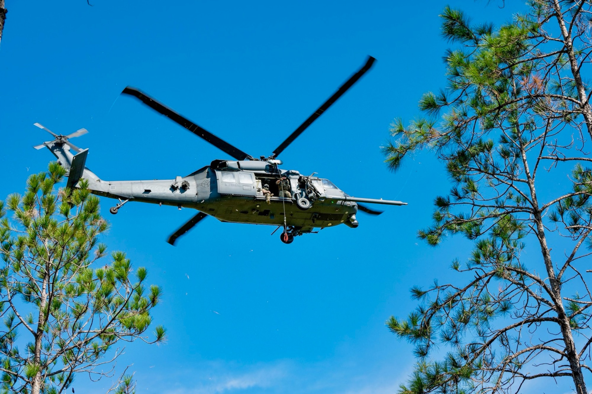 Special Missions Aviators inside an HH-60G Pave Hawk helicopter search for a simulated isolated person during a skills-based competition event at Avon Park Air Force Range, Florida, Nov. 7, 2023. This skills-based competition brings together combat search and rescue squadrons from around the world, offering valuable training and skill development as participants learn from each other's techniques, tactics and experiences. (U.S. Air Force Courtesy Photo)