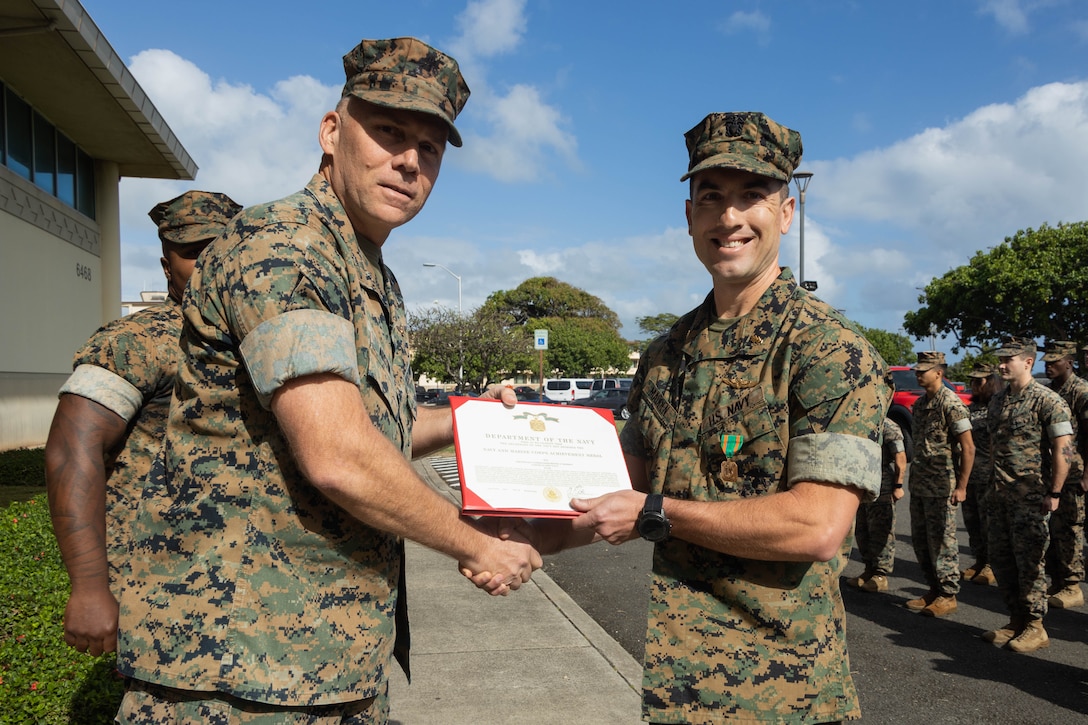 U.S. Marine Corps Maj. Gen. Eric Austin, 1st Marine Aircraft Wing (MAW) commanding general, and U.S. Navy Lt. Cmdr. Dennis Madden, Safety Officer of Marine Aircraft Group (MAG) 24, 1st MAW, pose for a photo at MAG-24 Headquarters, Marine Corps Base Hawaii, March 28, 2024. Madden was selected as the 1st MAW Safety Professional of the 2023 Fiscal Year and was awarded the Navy and Marine Corps Achievement Medal for creating and sustaining significant enhancements to 1st MAW. (U.S. Marine Corps photo by Lance Cpl. Tania Guerrero)