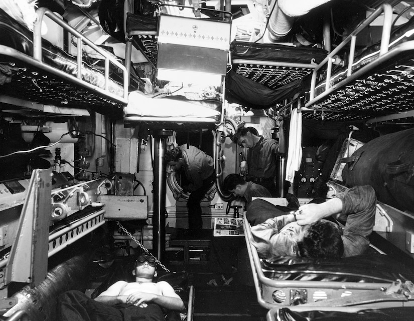 Men relax in a small submarine space.