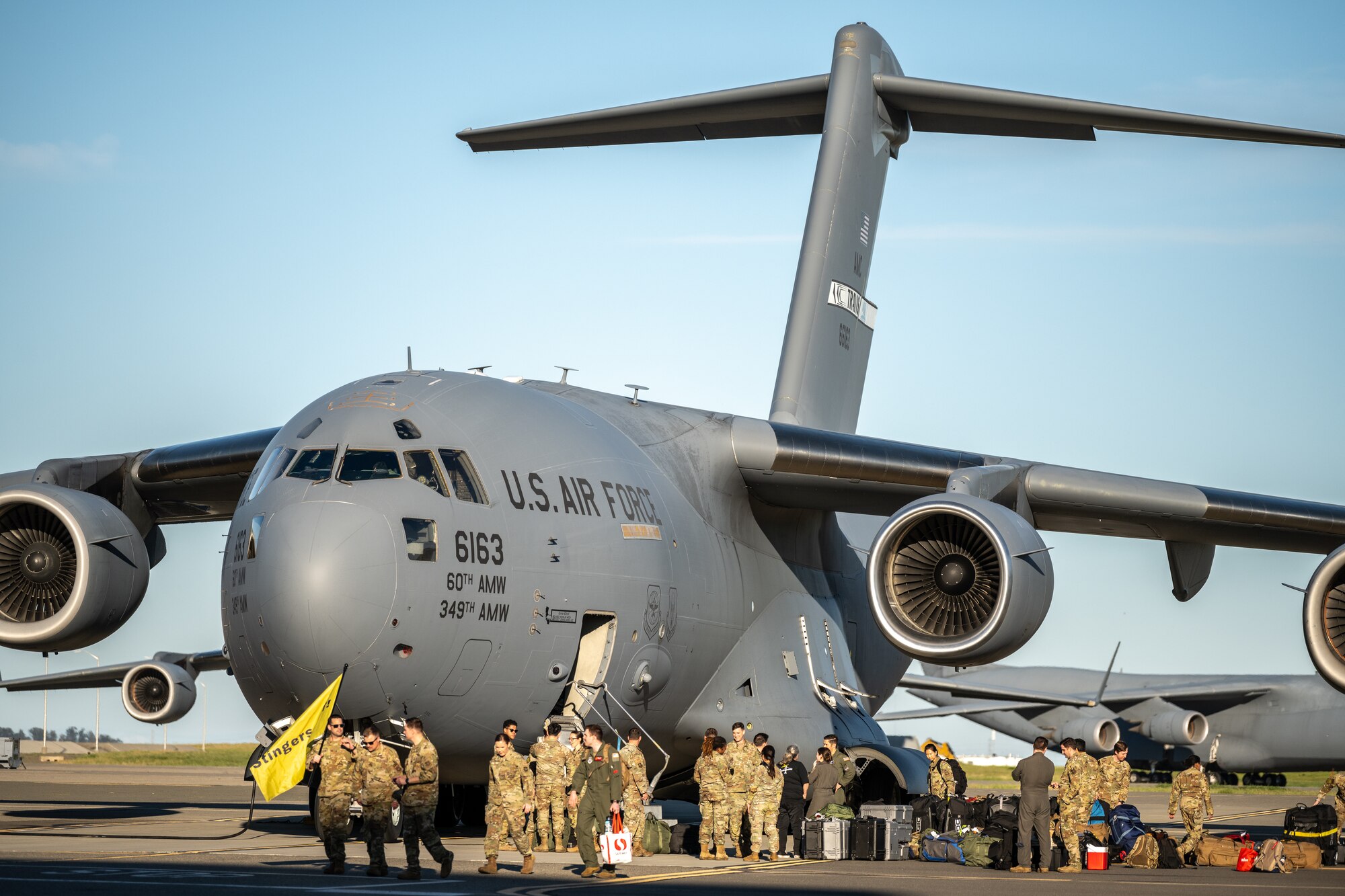 A group of Airmen greet and unload equipment from a C-17 Globemaster III after a deployment