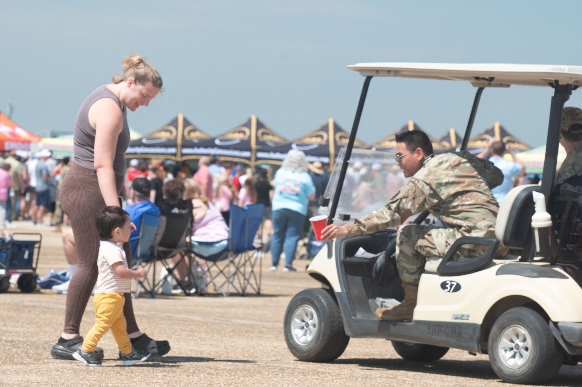 Airman gives water to a child during the Beyond the Horizon Air and Space Show at Maxwell Air Force Base, Ala. April 7, 2024. The air and space show boasted a variety of activities, including military and civilian aerial demonstrations, static display aircraft, and a STEM expo. (U.S. Air Force Photo by Senior Airman Greydon Furstenau)