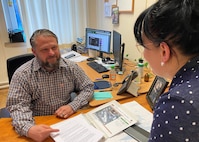 Bryce Williams, a plans and operations specialist at Logistics Readiness Center Rheinland-Pfalz, shows his coworker, Nicole Anderson, a report at his office on Daenner Kaserne in Kaiserslautern, Germany, April 10. Williams is responsible, in part, for sending out weekly reminders on suspense dates, working taskers, and compiling and sending comprehensive reports.