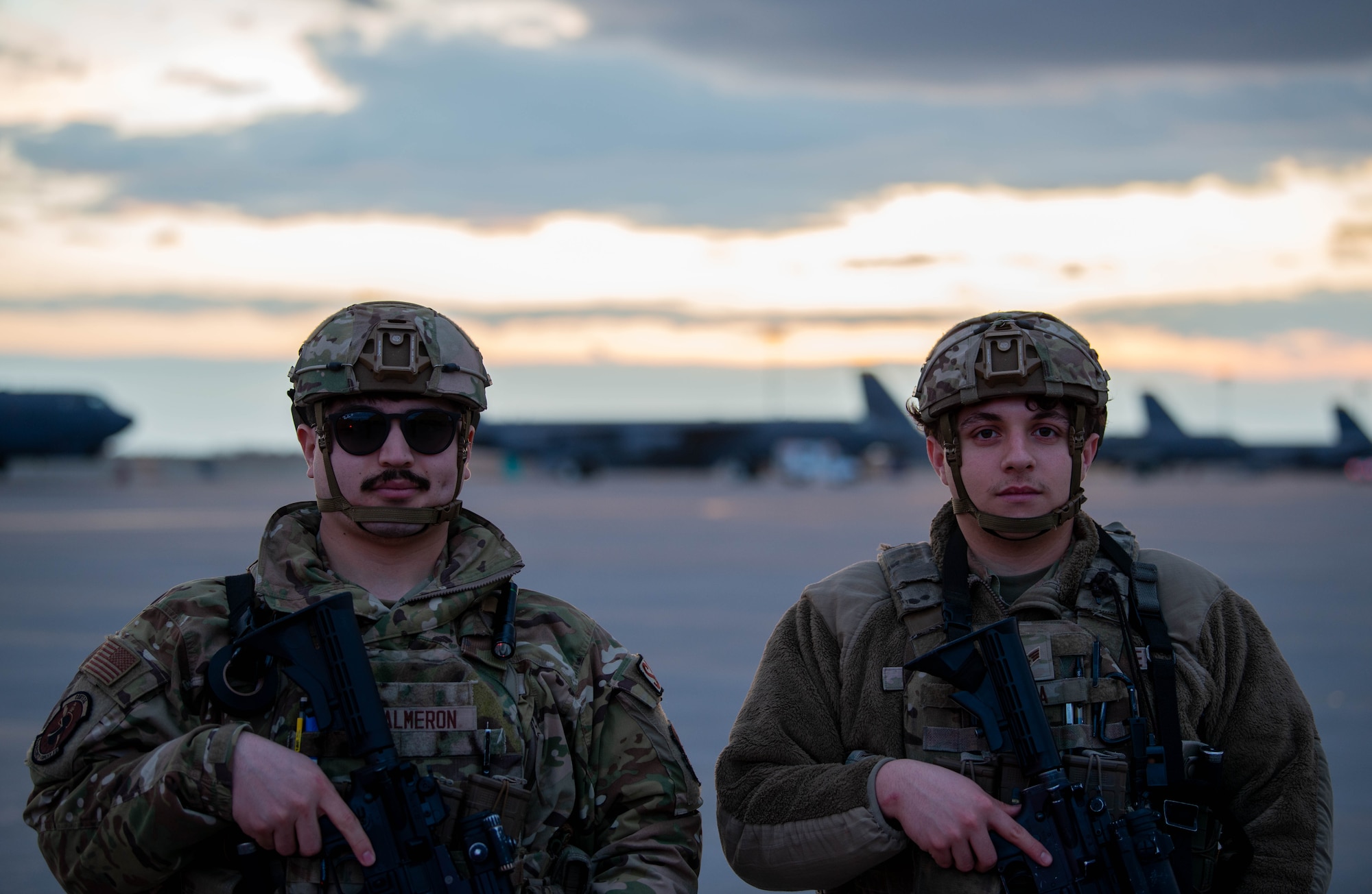Airman Jonathan Salmeron, 5th Security Forces Squadron defender, (left) and Senior Airman Jose Soiza, 5th Security Forces Squadron defender, pose on the flightline during Exercise Prairie Vigilance/Bayou Vigilance 24-3 at Minot Air Force Base, North Dakota, April 8, 2024. Exercises like Prairie Vigilance continually develop Airmen and aircrew skill sets by improving operational capabilities and increasing mission readiness. (U.S. Air Force photo by Airman 1st Class Luis Gomez)
