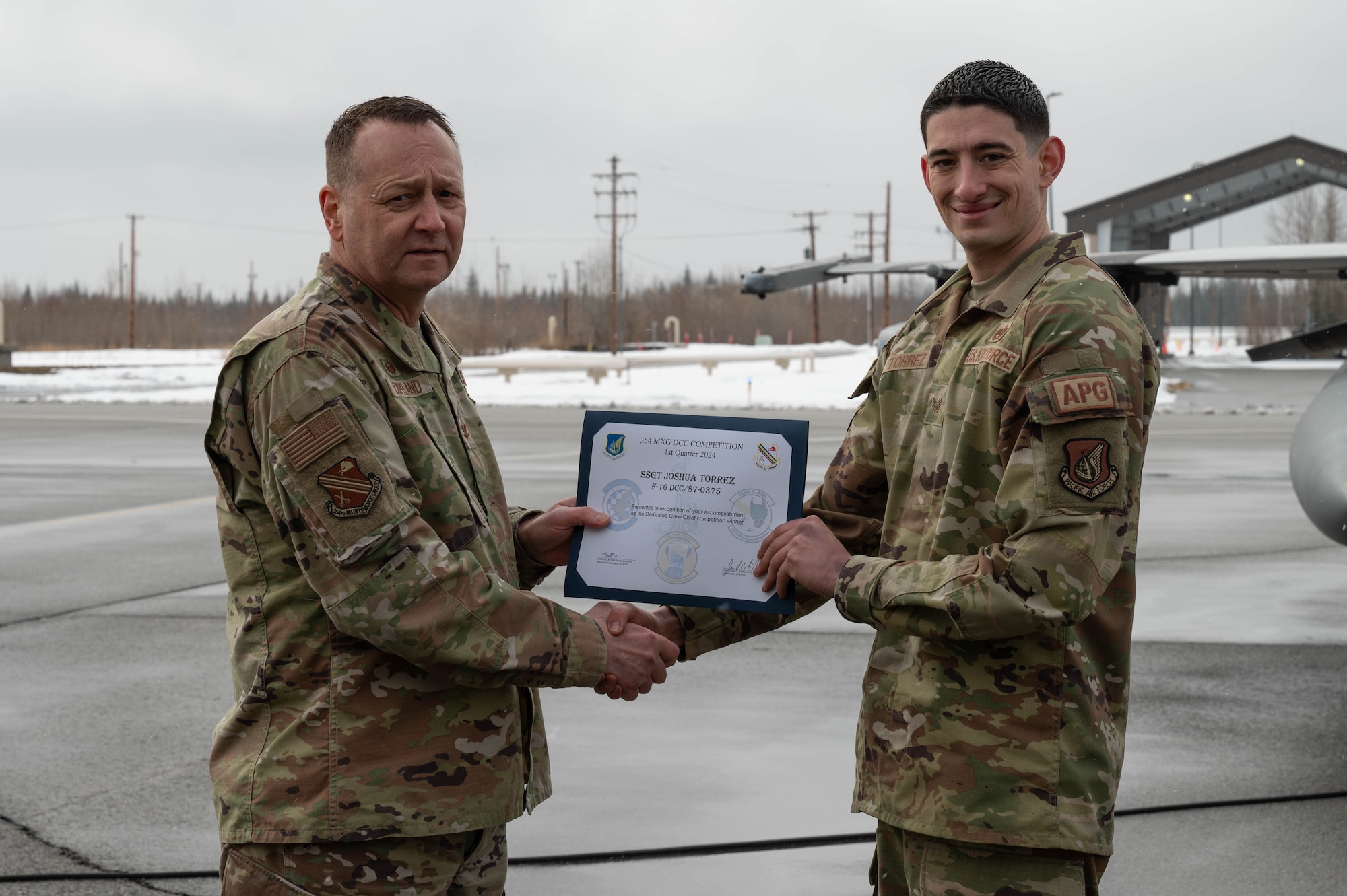U.S. Air Force Col. Jerrymar Copeland, 354th Maintenance Group commander, left, presents a Dedicated Crew Chief award certificate to Staff Sgt. Joshua Torrez, 18th Fighter Generation Squadron dedicated crew chief, following a load competition at Eielson Air Force Base, Alaska, April 5, 2024.