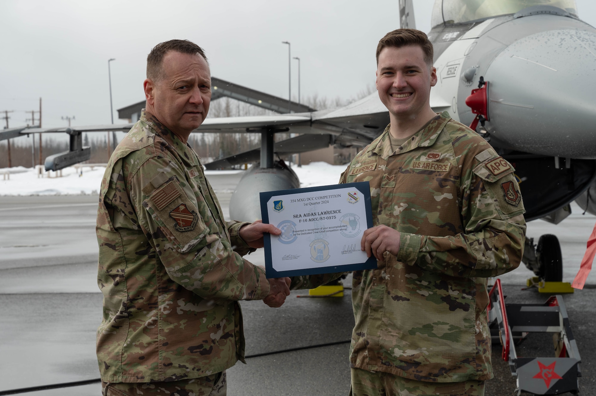 U.S. Air Force Col. Jerrymar Copeland, 354th Maintenance Group commander, left, presents a Dedicated Crew Chief award certificate to Senior Airman Aidan Lawrence, 18th Fighter Generation Squadron assistant dedicated crew chief, following a load competition at Eielson Air Force Base, Alaska, April 5, 2024.