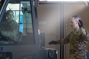 Airman using his hands to direct a forklift as it reverses