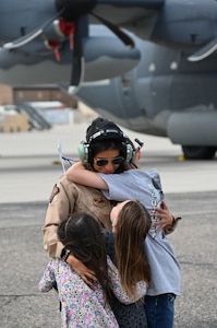 An Air Force Captain hugs her three young children on a flightline.